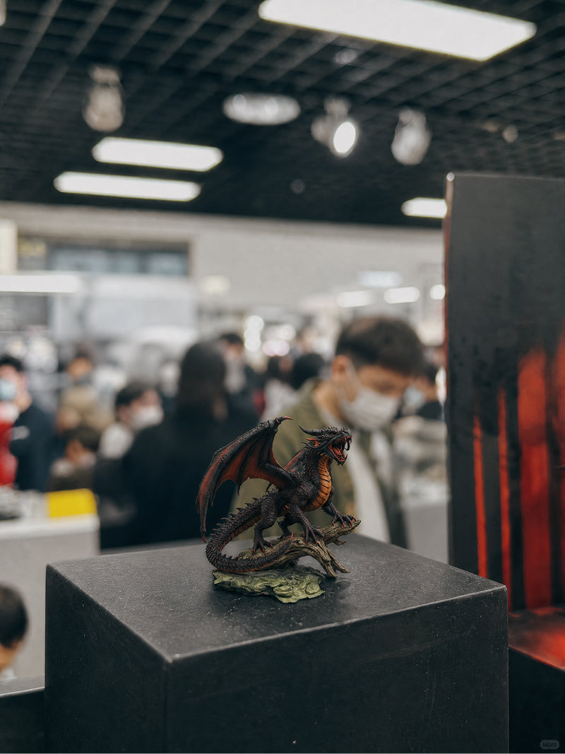 Custom red dragon figurine perched on driftwood at a collectible expo - JuJuBit