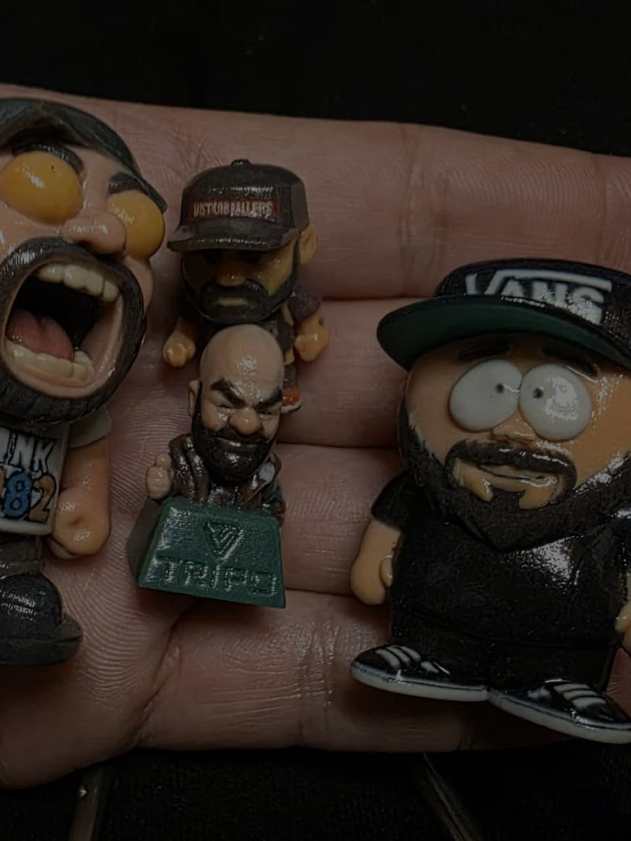 Custom keycap figurines held in hand, including a TRIPO-branded mini bust - JuJuBit