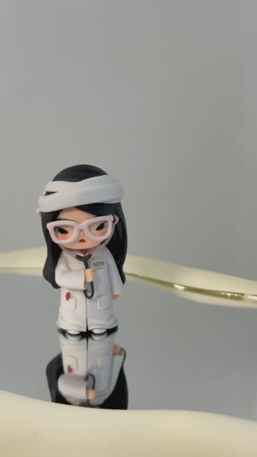 Custom nurse figurine with pink glasses and a stethoscope, unboxed beside a collectible display shelf - JuJuBit