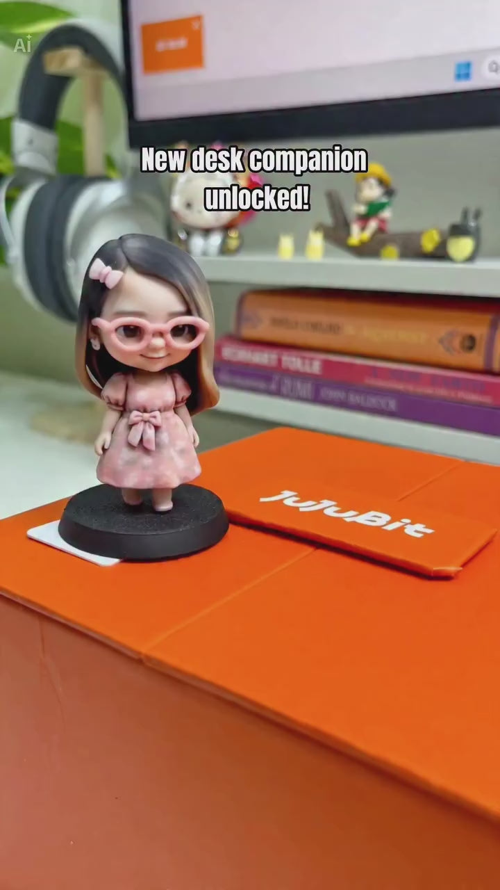 Custom desk figurine of a girl in pink glasses and a floral dress beside a JuJuBit order box and design preview - JuJuBit